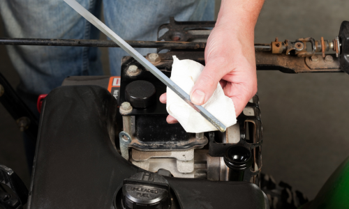 Person using a tool on a small engine, possibly a lawn mower engine.